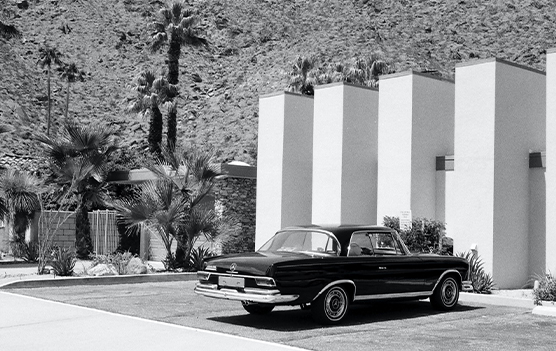vintage grayscale photography of gray coupe parked in front of white building